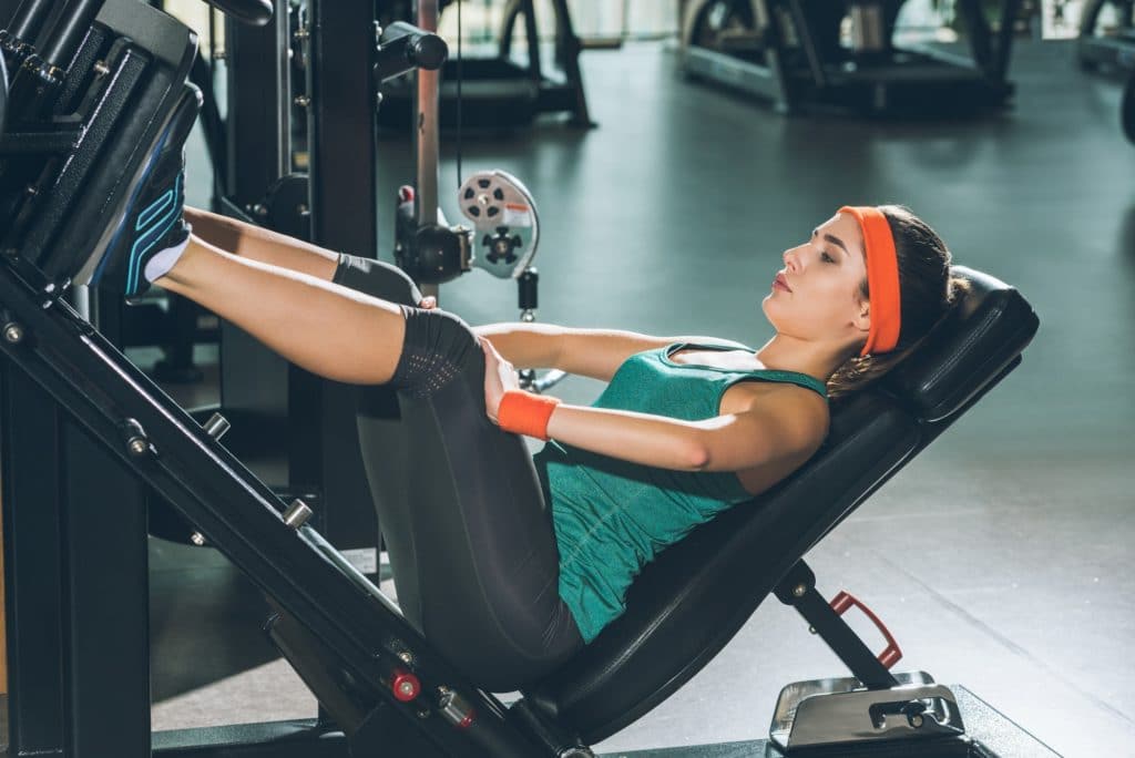 sporty woman training legs on training apparatus at gym